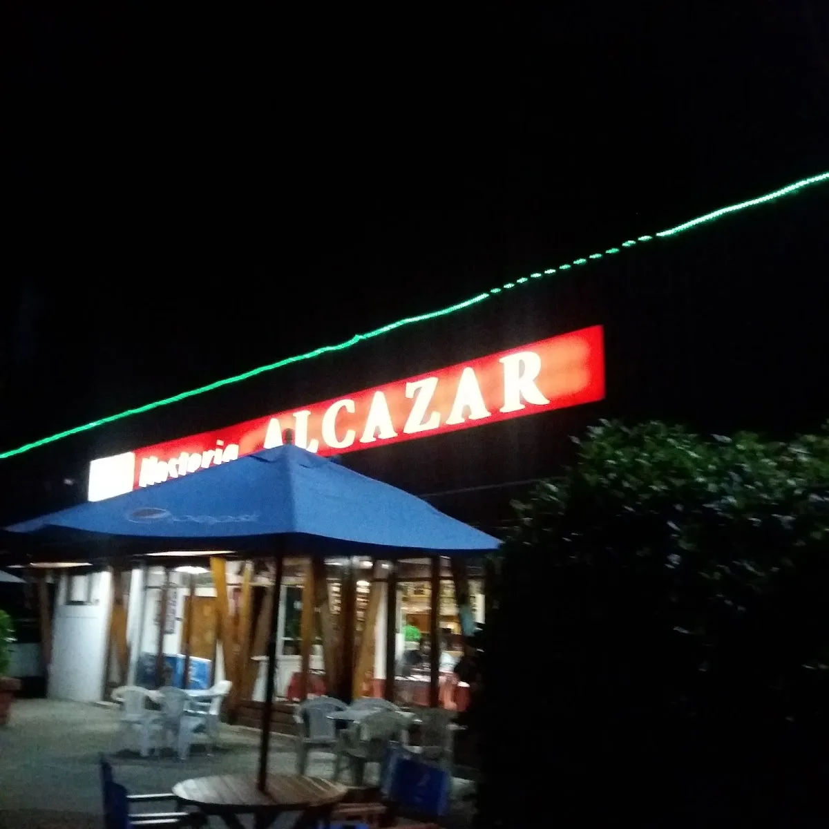 Entrada de Hostería Alcázar iluminada de noche con su letrero rojo