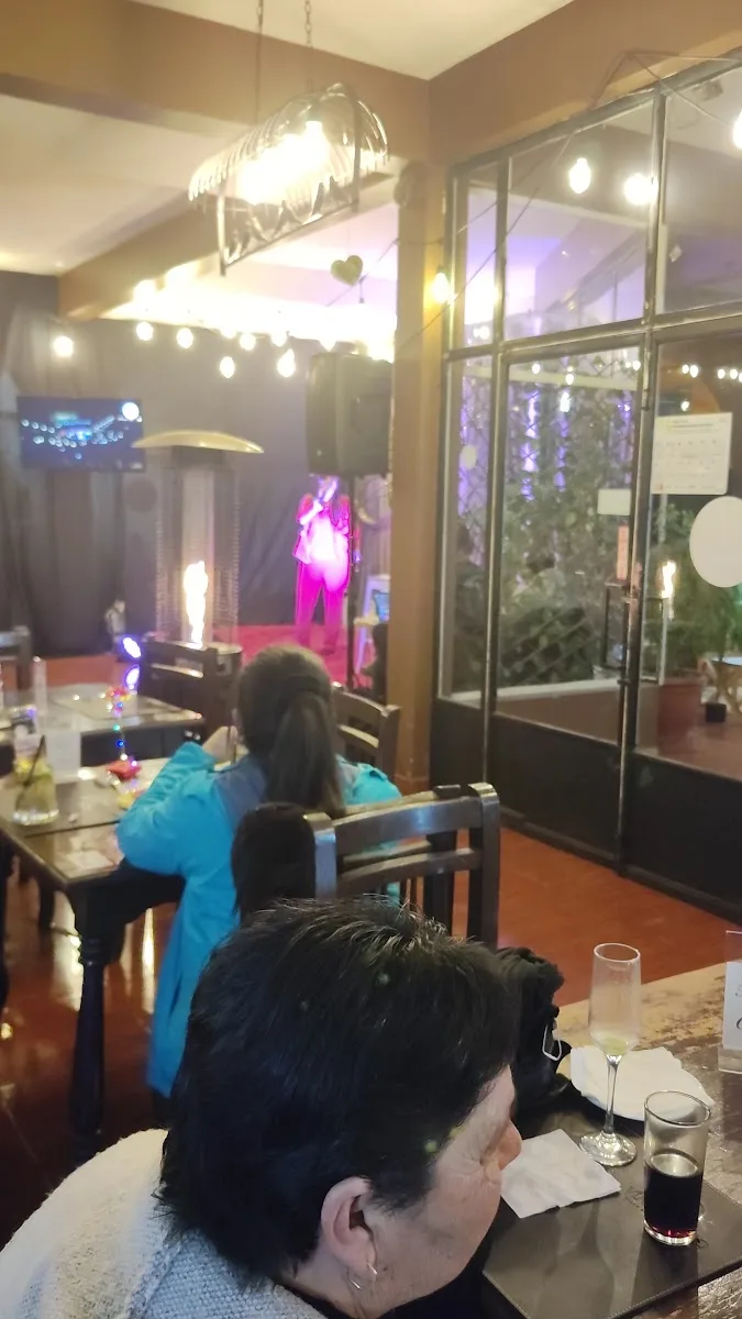 Interior del salón de noche con música y comensales en Hostería Hualañe
