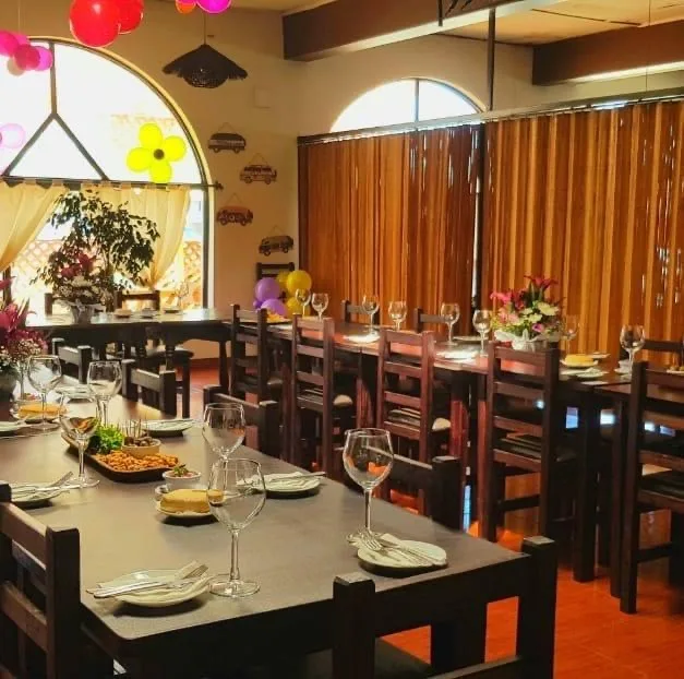 Comedor de la hostería con ventanas en arco, cortinas y manteles de cuadrillé