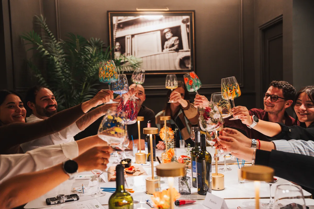 Brindis en Aldo's Bar: varias copas de vino y tragos de colores chocando sobre la mesa