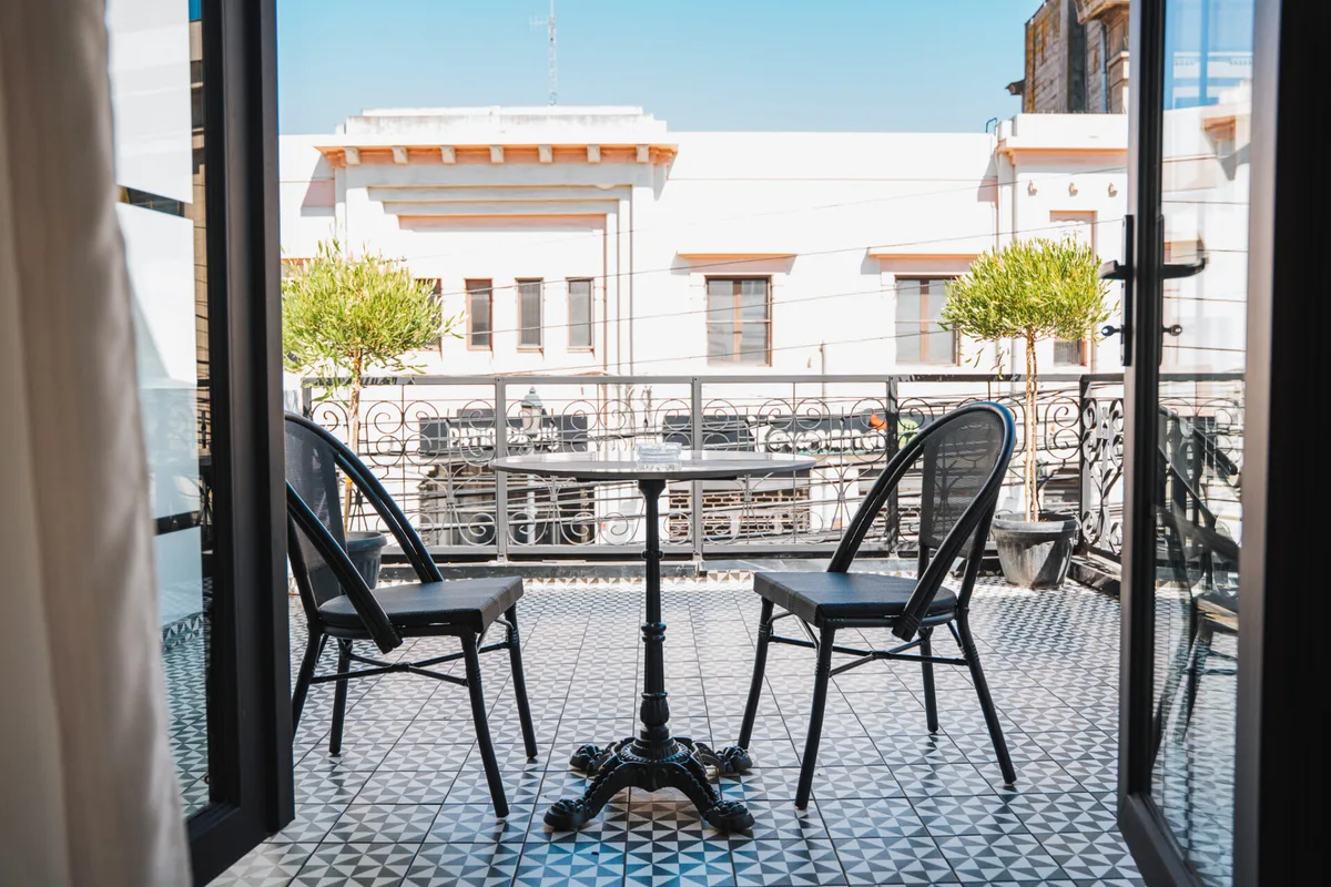 Entrada del Hotel Marcos Gamero: toldo verde, fachada blanca con enredaderas y una pasajera llegando con su maleta