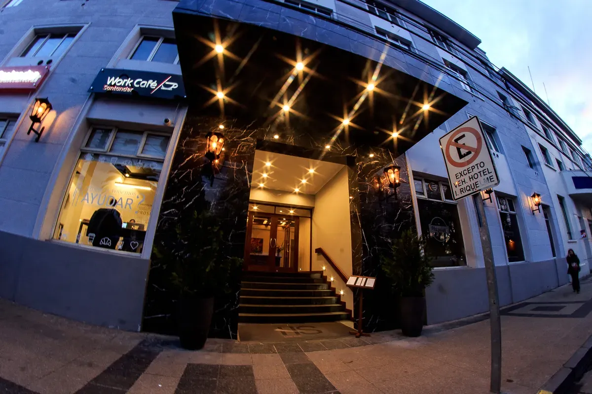 Entrada del hotel por Constitución: portal de mármol negro con faroles encendidos