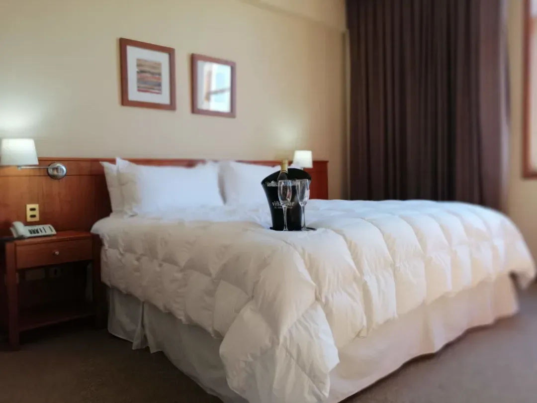 Habitación matrimonial del Gran Hotel Isabel Riquelme con cortinaje oscuro y veladores encendidos