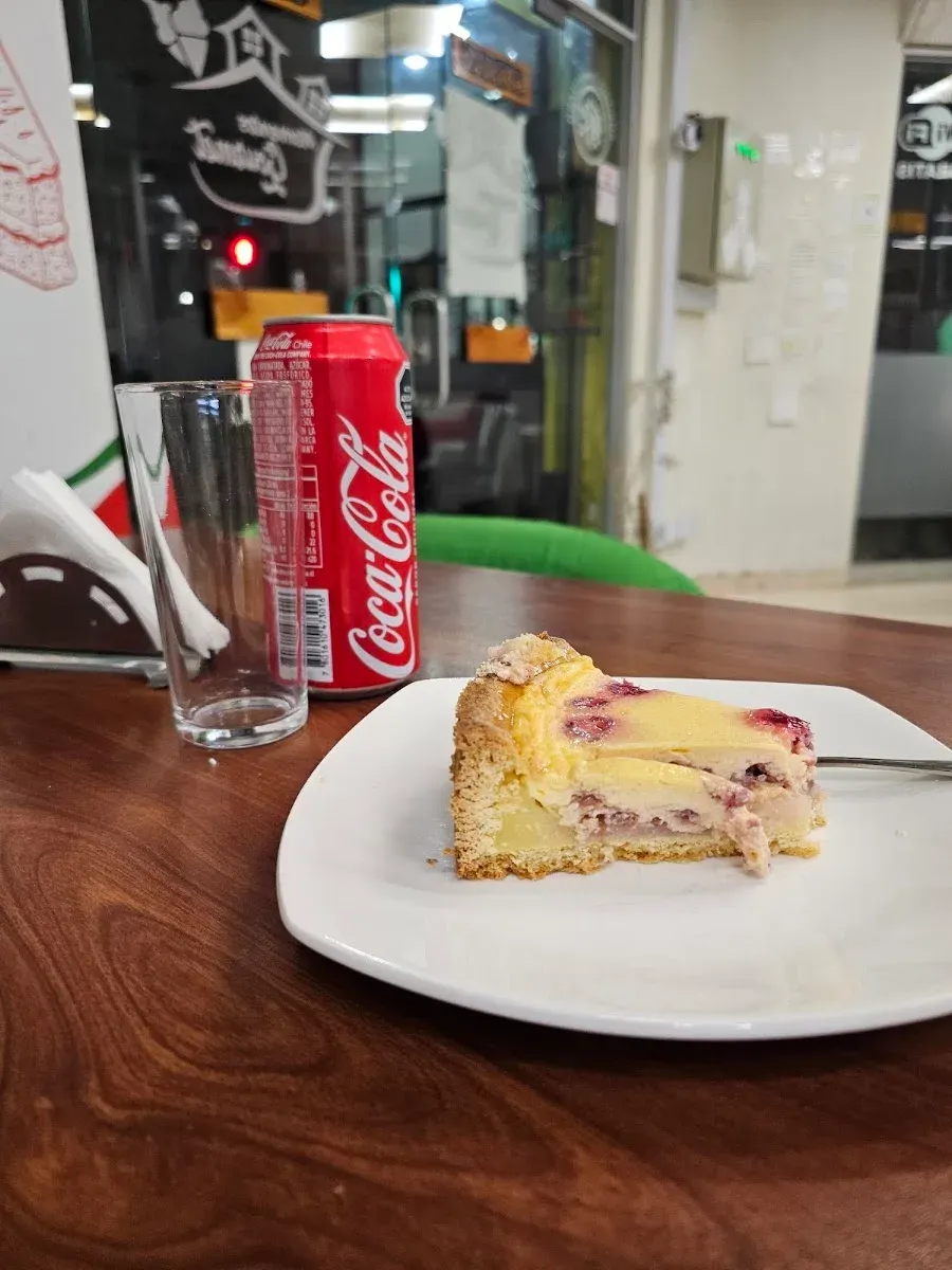 Porción de kuchen de frutos rojos junto a una bebida de la casa