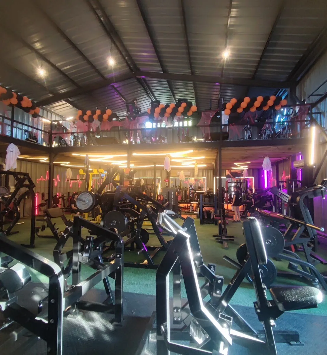 Interior del gimnasio de noche con luces de neón rosadas