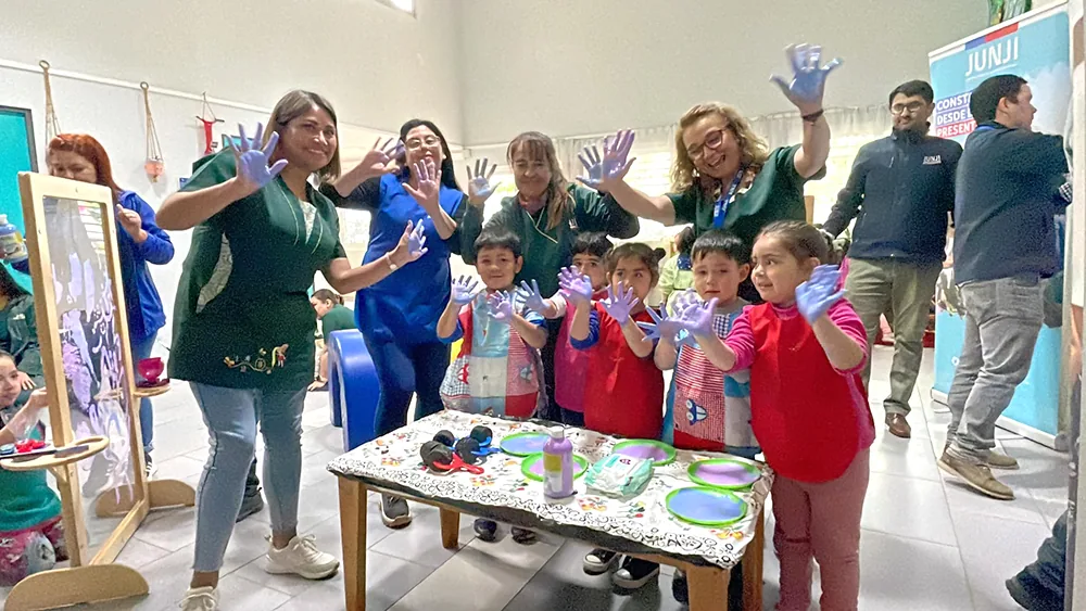 Educadoras y párvulos del Jardín Lucerito mostrando las manos pintadas de morado