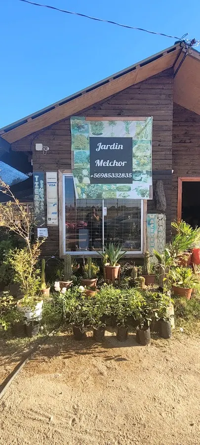 Entrada del jardín El Canelo, con el cartel y plantas en la vereda