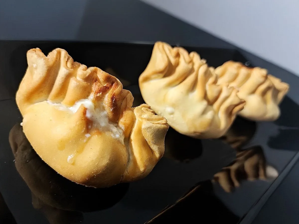 Gyosas doradas servidas en plato negro con limón