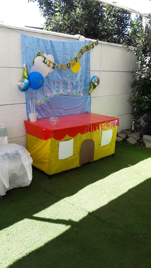 Salón techado de Kid Mania con mesas de cumpleaños sobre pasto sintético