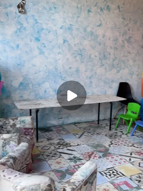 Interior del local de Kids Art: mesa de trabajo, pared decorada y sillas de colores