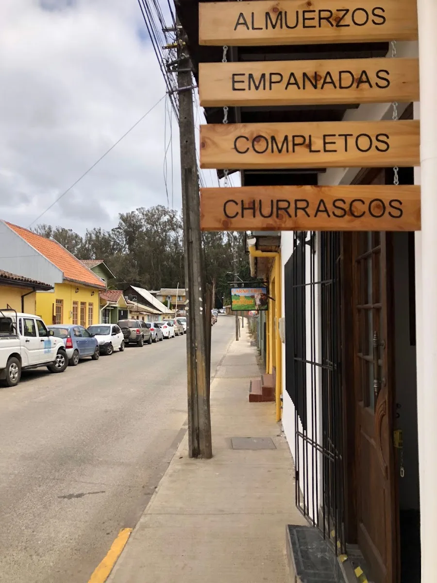 Tablillas de madera colgando en la vereda: almuerzos, empanadas, completos y churrascos