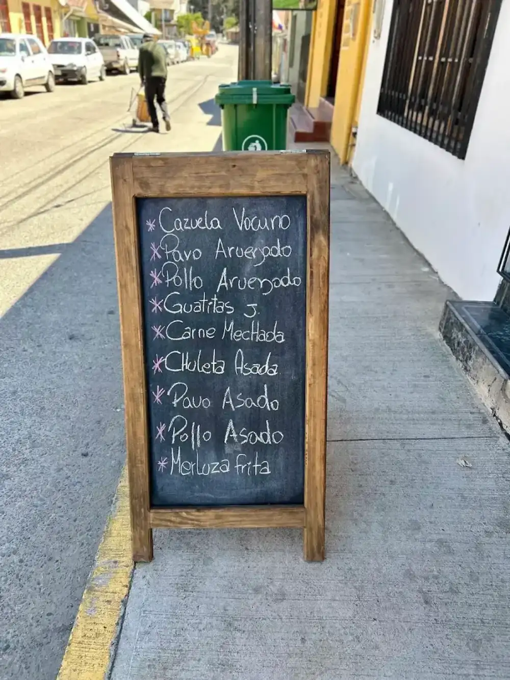 Pizarra de madera en la vereda con el menú del día escrito a tiza
