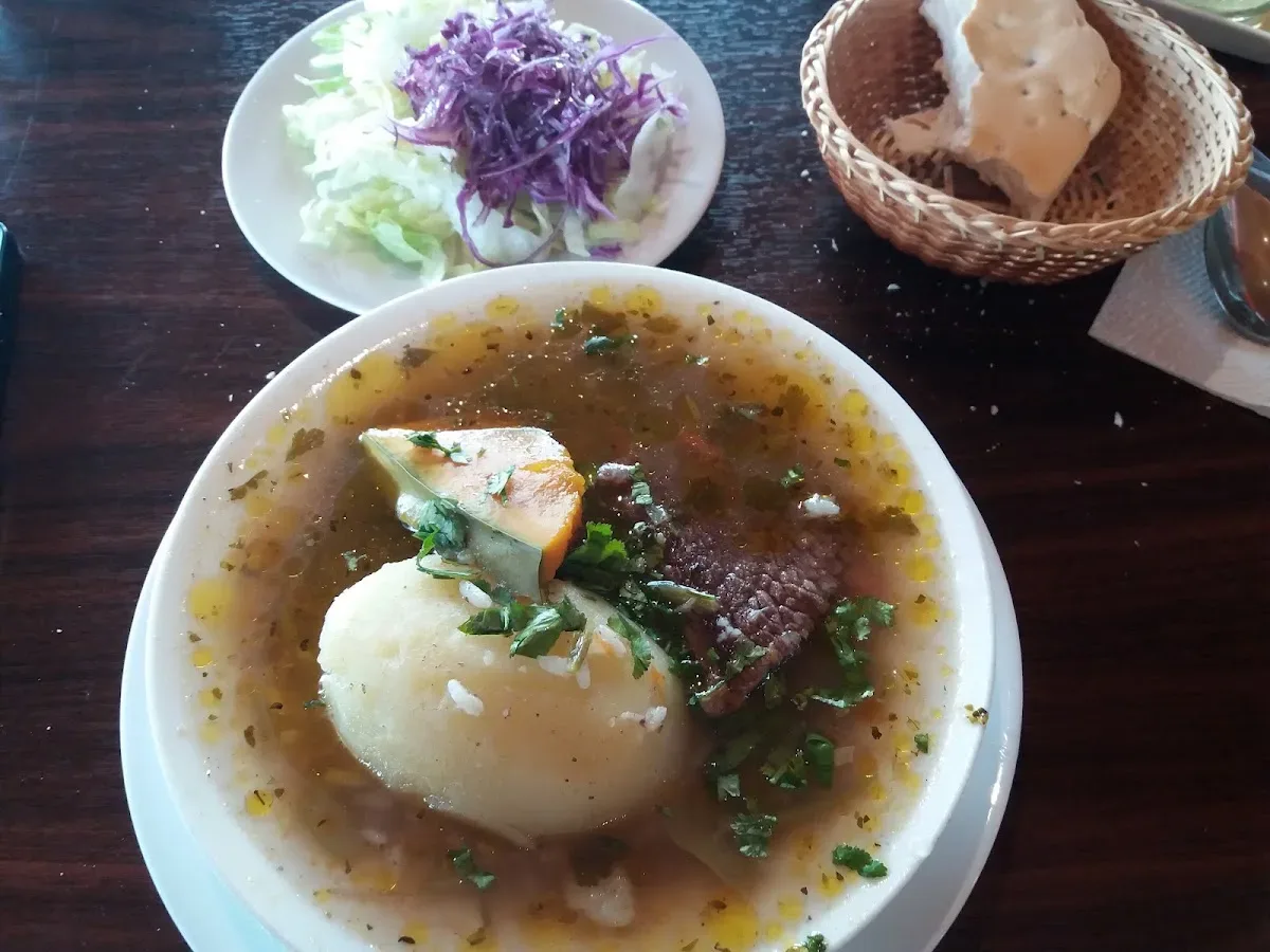 Cazuela con carne, papa y huevo servida en plato de greda