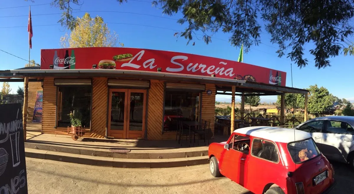 Fachada de La Sureña: letrero rojo y terraza con sombrillas en la Entrada Sur de Molina