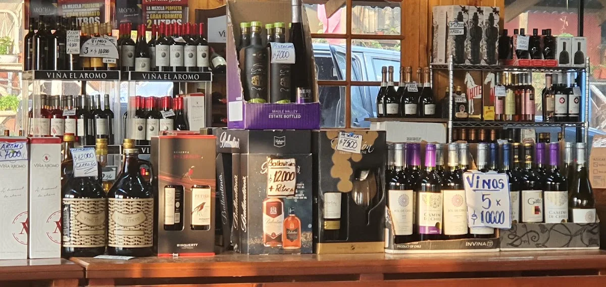 Estante de la botillería con botellas de vino del valle del Maule y carteles de oferta escritos a mano