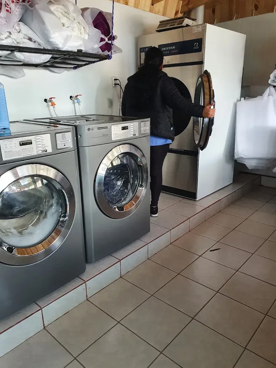 Secadora industrial Dexter siendo cargada con ropa en la lavandería