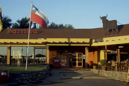 Fachada de día de Los Ganaderos con la bandera chilena