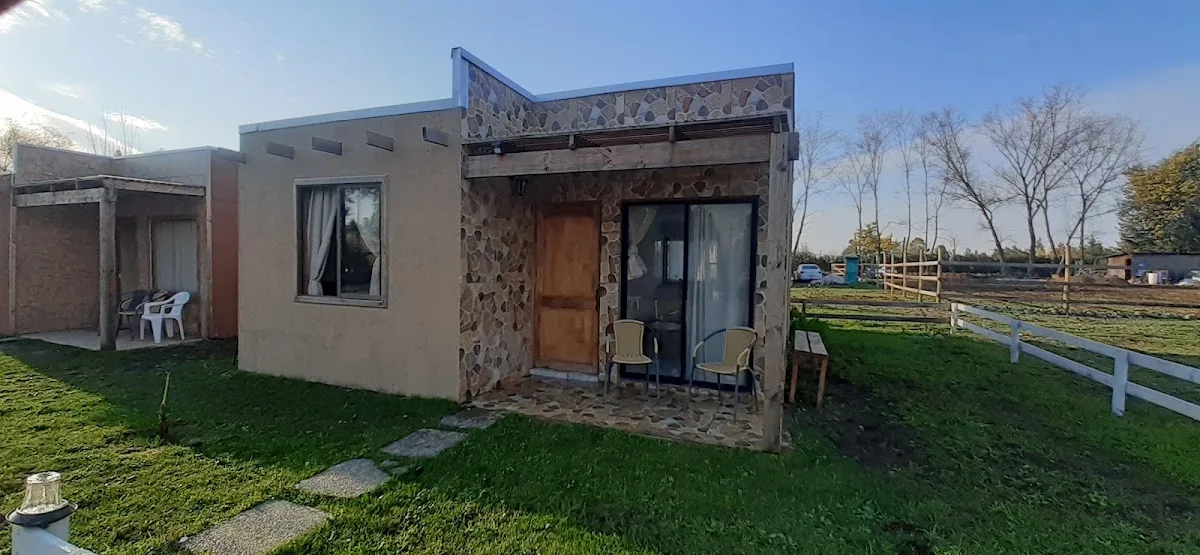 Cabaña de madera de Los Treiles rodeada de áreas verdes, con cierre blanco