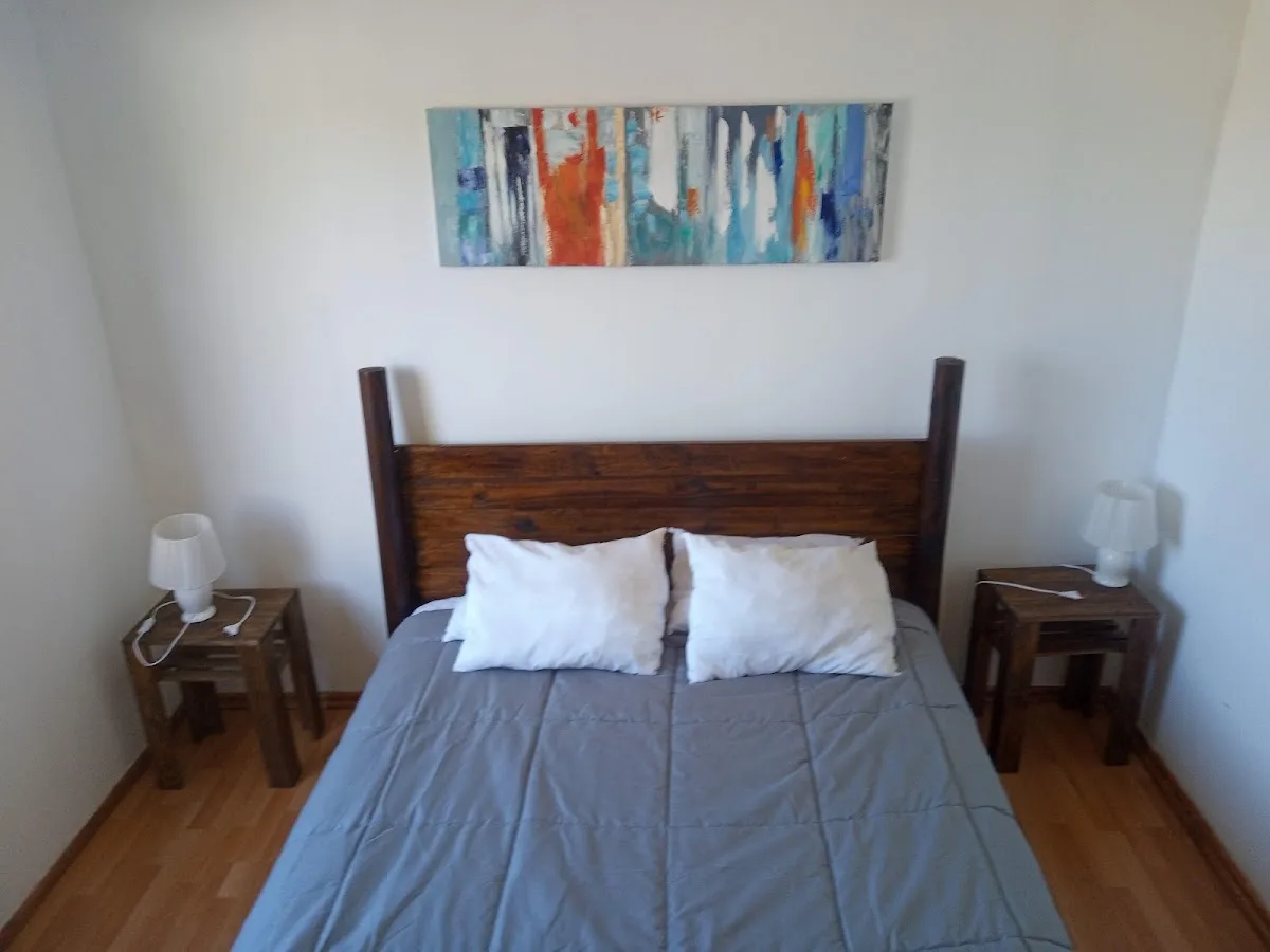 Dormitorio de cabaña en Los Treiles: cama con ropa de cama clara y paredes de madera