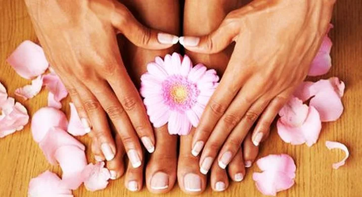 Manicura terminada de Luze Vital: uñas cuidadas junto a flores rosadas