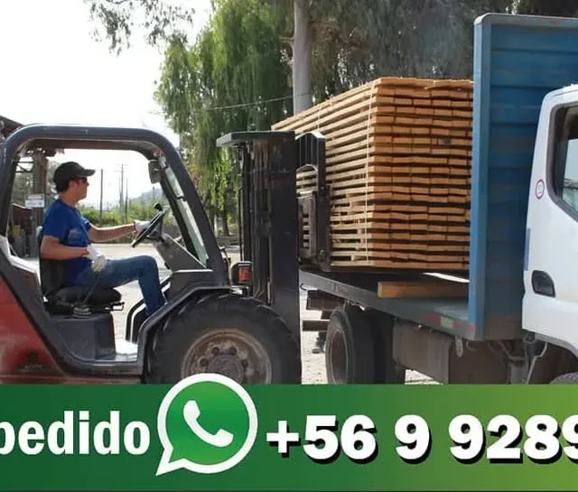 Grúa horquilla cargando un camión con madera en el patio de la barraca