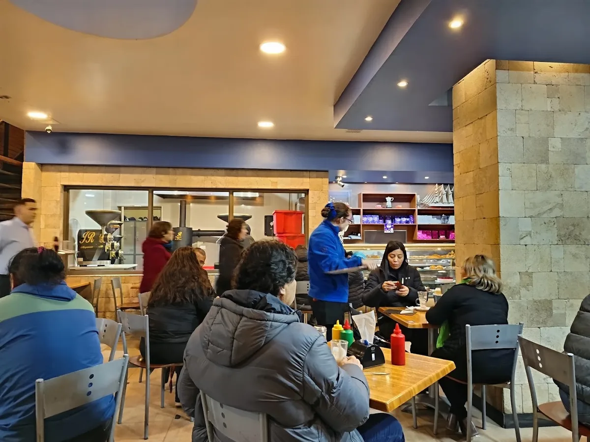 Salón de Café Marbella con clientes en las mesas, paredes color café y luz cálida