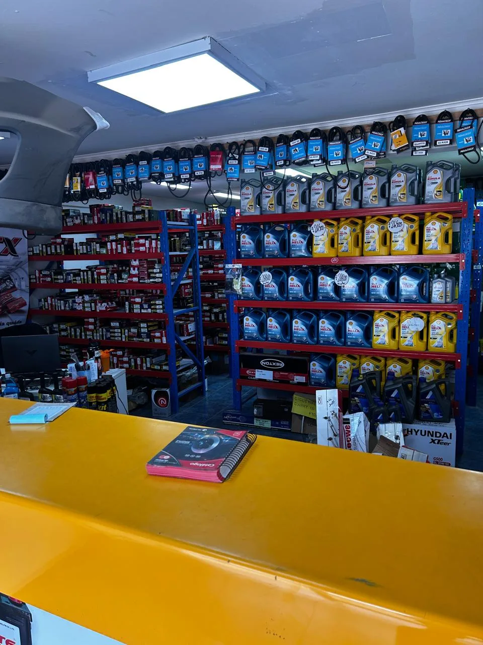 El mesón amarillo de la tienda con repisas de aceites y repuestos detrás