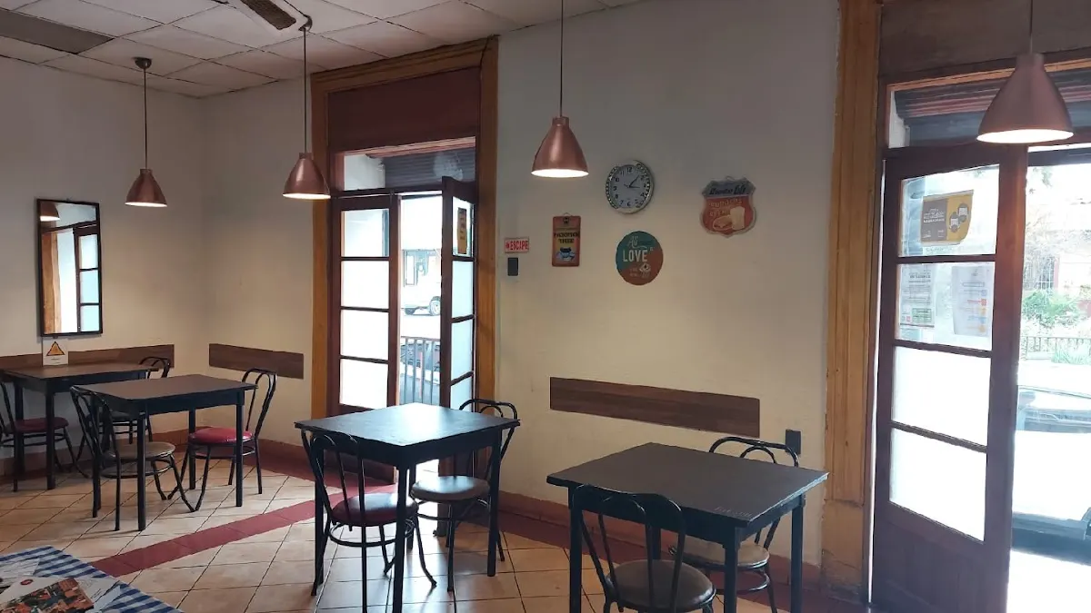 Salón del Mesón de Romeral: mesas de madera, lámparas de cobre colgantes y puertas en arco