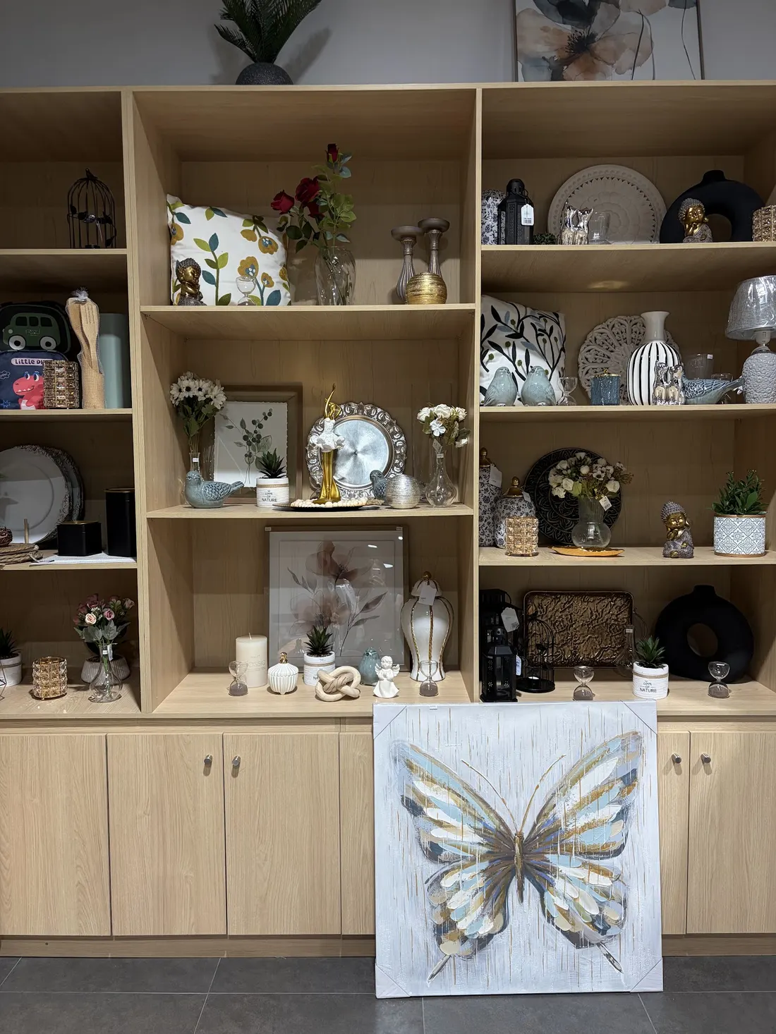 Vitrina de la tienda: repisas de madera con cuadros, jarrones, velas y objetos decorativos
