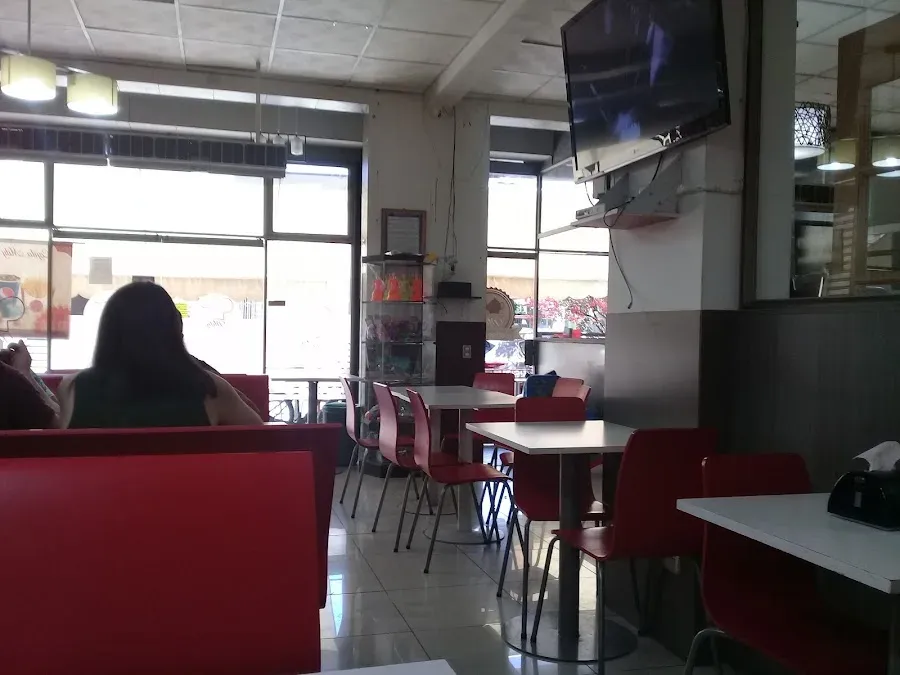 Salón del restaurant con sillas tapizadas en rojo y televisor