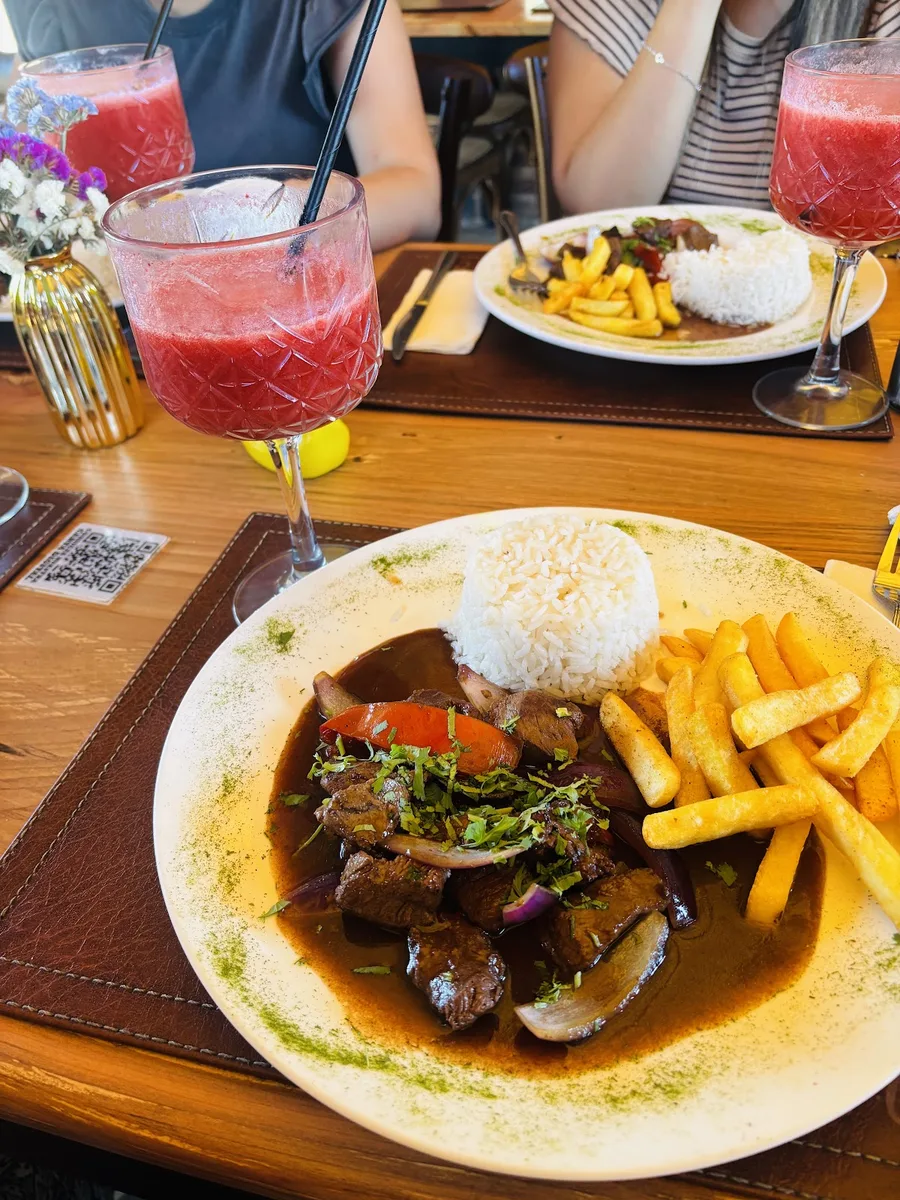 Plato de carne a la parrilla con arroz y papas fritas, acompañado de tragos