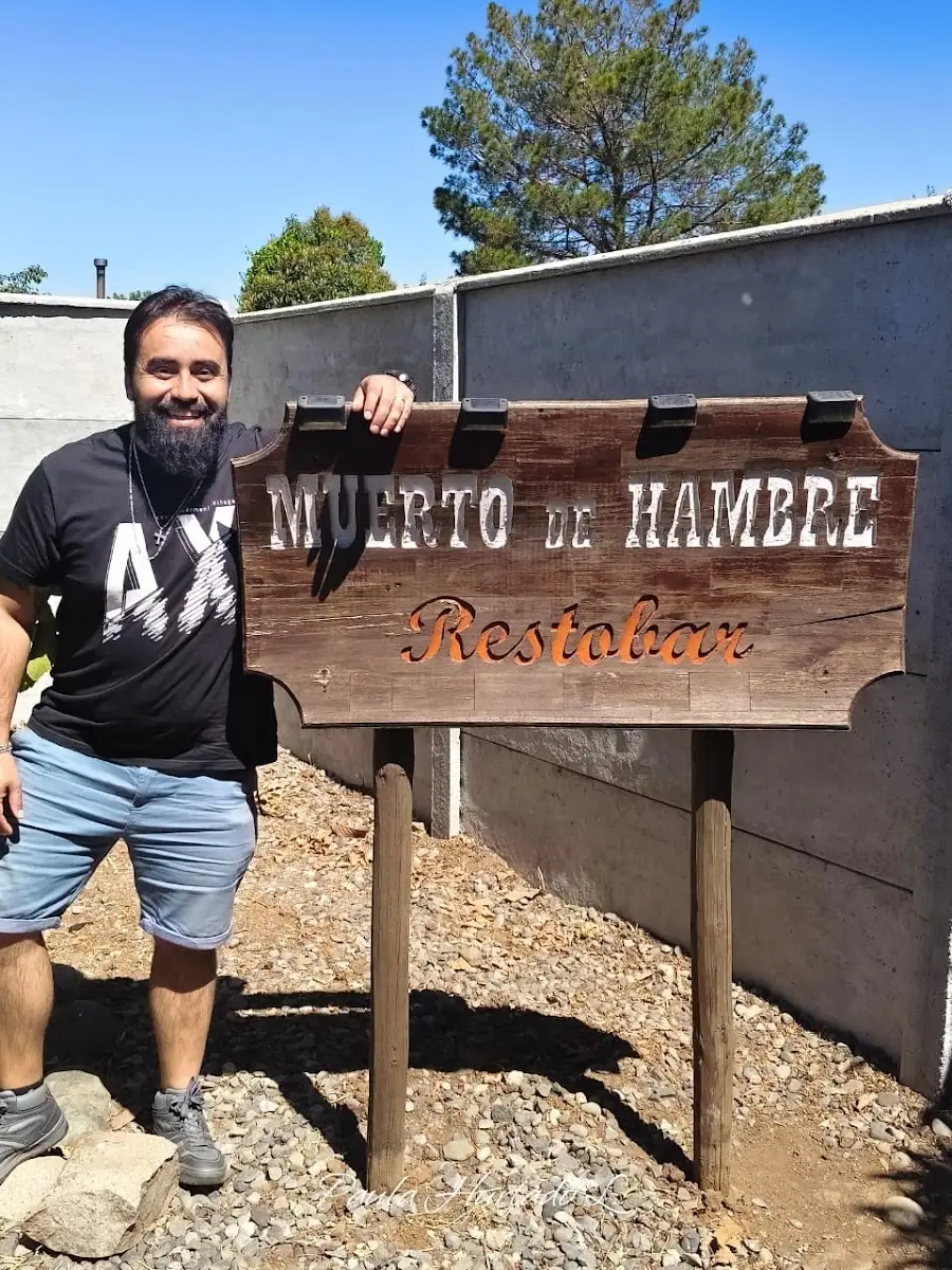 Letrero de madera tallada de Muerto de Hambre Restobar, con su personaje western
