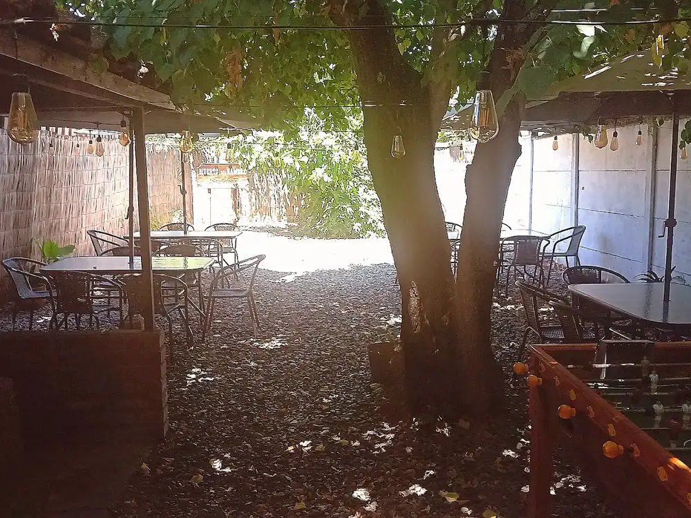 Terraza techada del restobar con mesas de madera