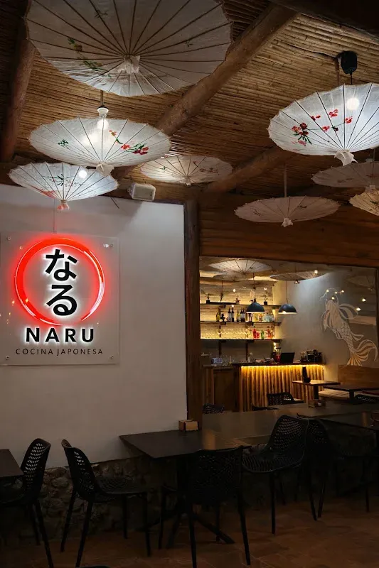 Salón del local NARU con su logo rojo en la pared y sombrillas colgadas