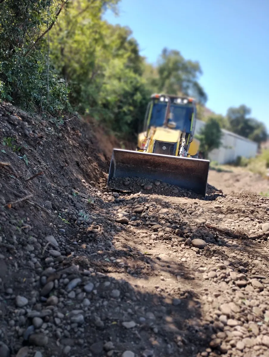 Retroexcavadora de OASS empujando ripio en una faena de San Clemente