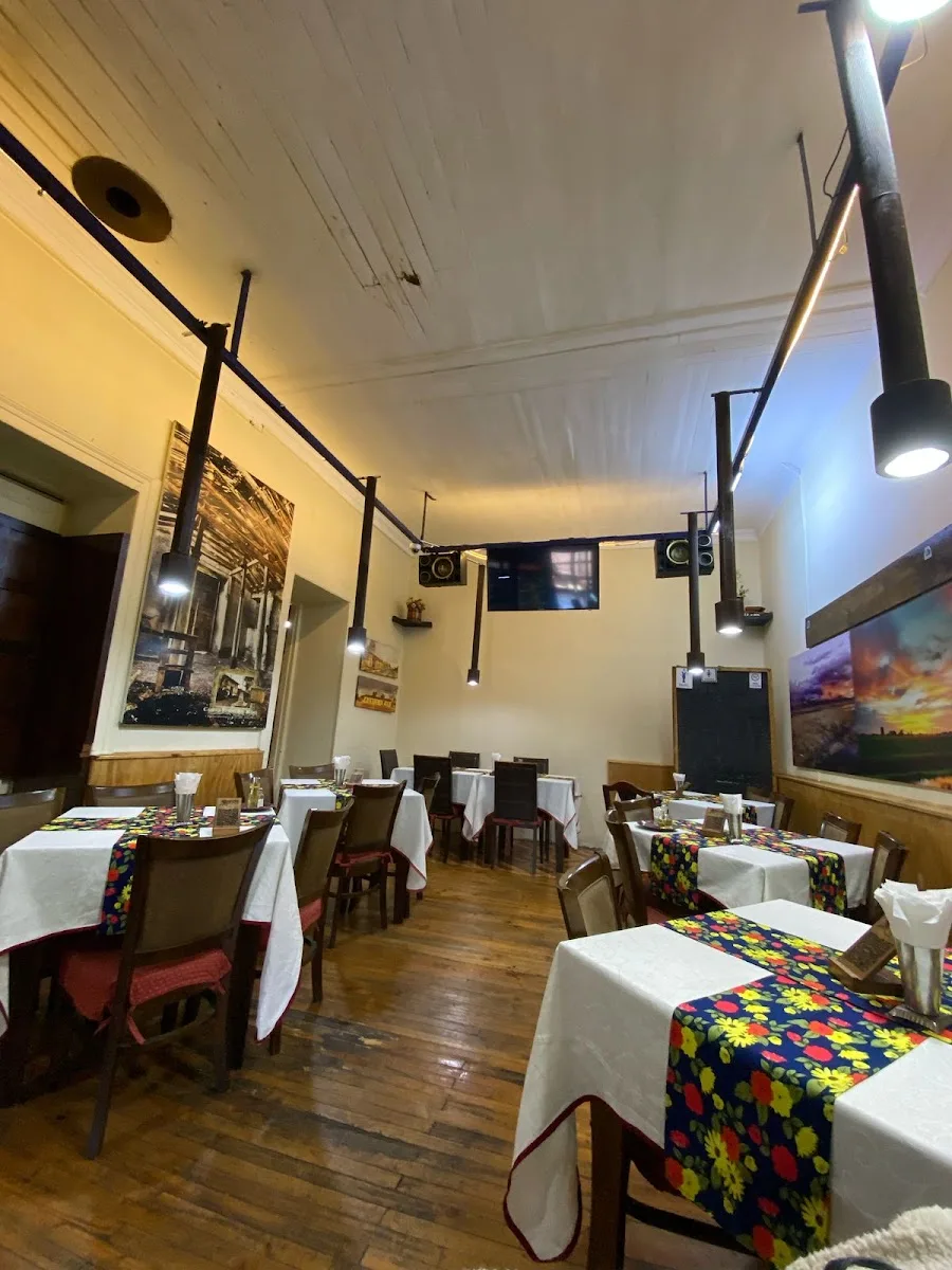 El salón de Oikos Pizzas en Molina: mesas con manteles florales y la vitrina, foto de su ficha de Google