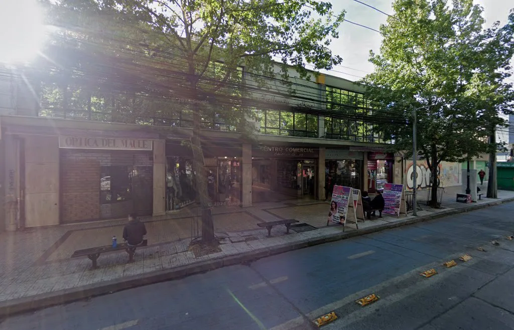 Fachada real de Óptica del Maule: letrero de madera sobre la puerta junto a la galería de 6 Oriente, Talca