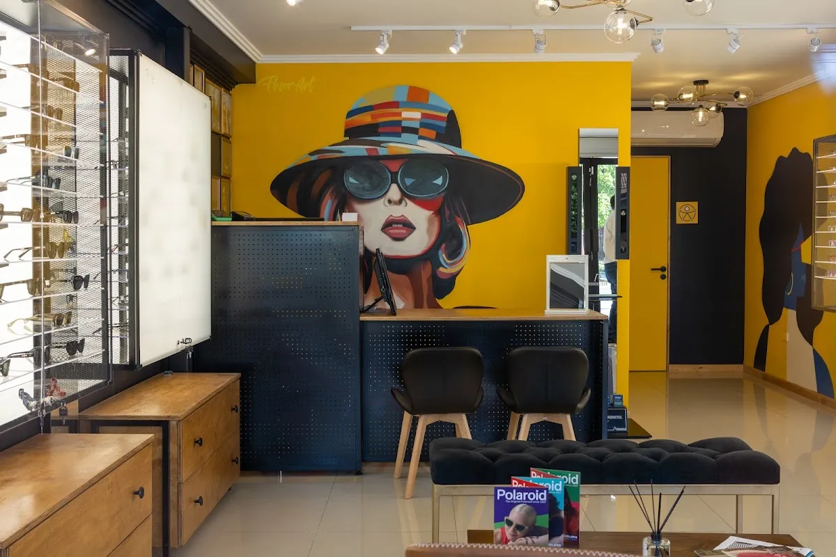 Interior de Óptica Loica con muro de armazones y mural amarillo pintado