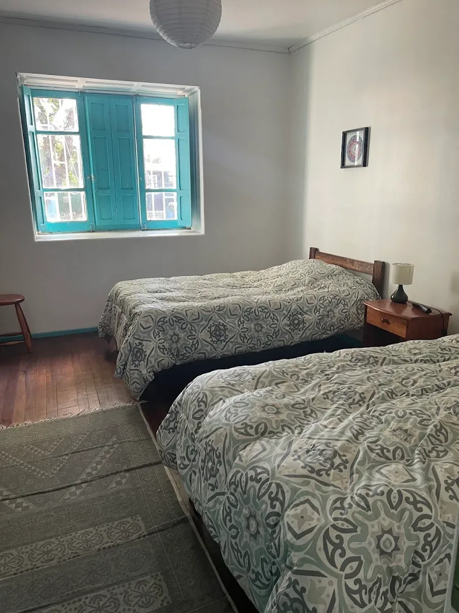 Habitación con dos camas de una plaza y ventanal turquesa