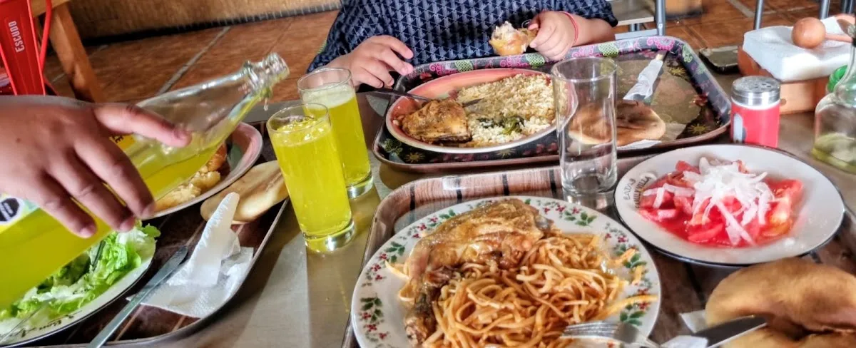 Mesa servida de La Paila de Huevos: pollo, tallarines, ensalada chilena, pan amasado y bebida