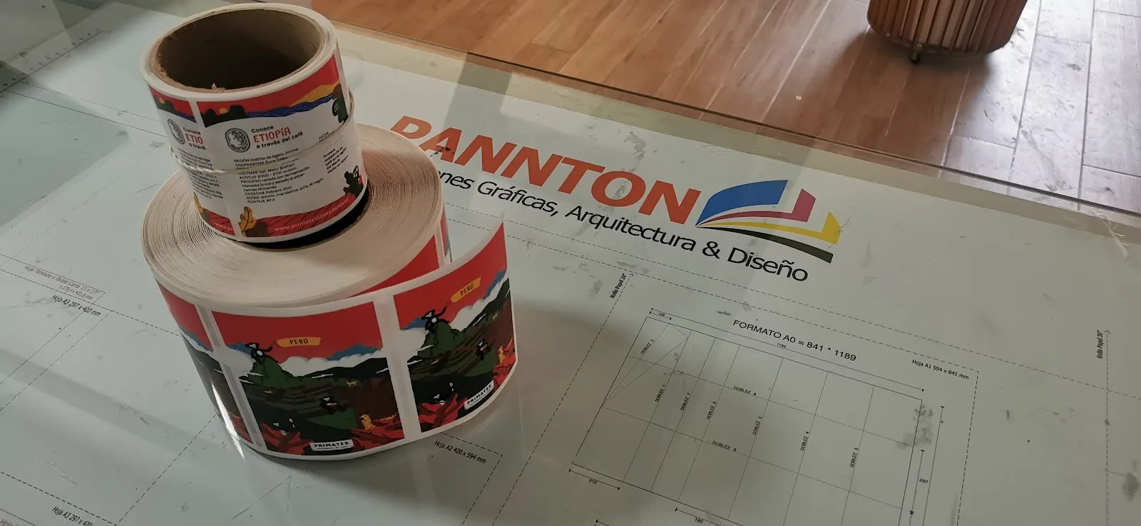 Rollo de adhesivos impresos con la marca Pannton sobre la mesa de trabajo