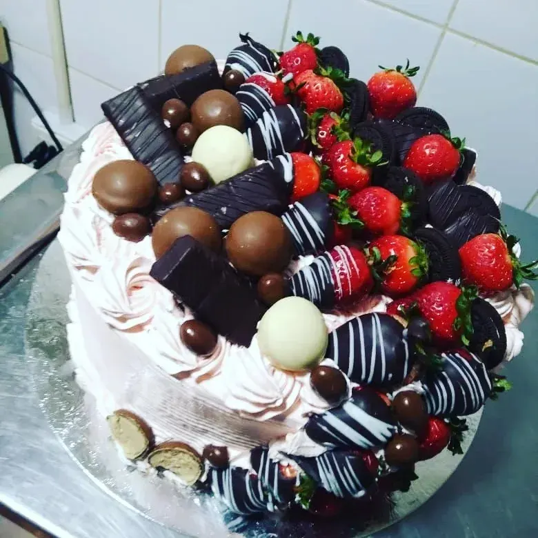 Kuchen de frutas con kiwi, durazno y cerezas en exhibidor
