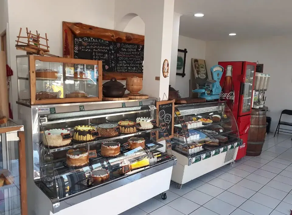 Interior de Pastelería Florencia: vitrinas llenas de tortas, pizarras con la carta y el local ordenado de Quechereguas
