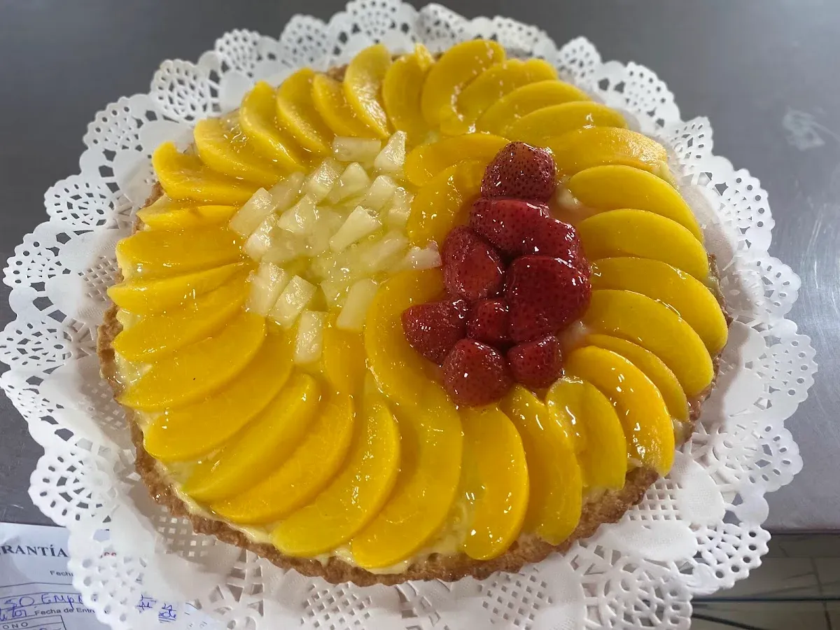 Torta de frutas de Mi Cabaña con duraznos, frambuesas y piña sobre blonda