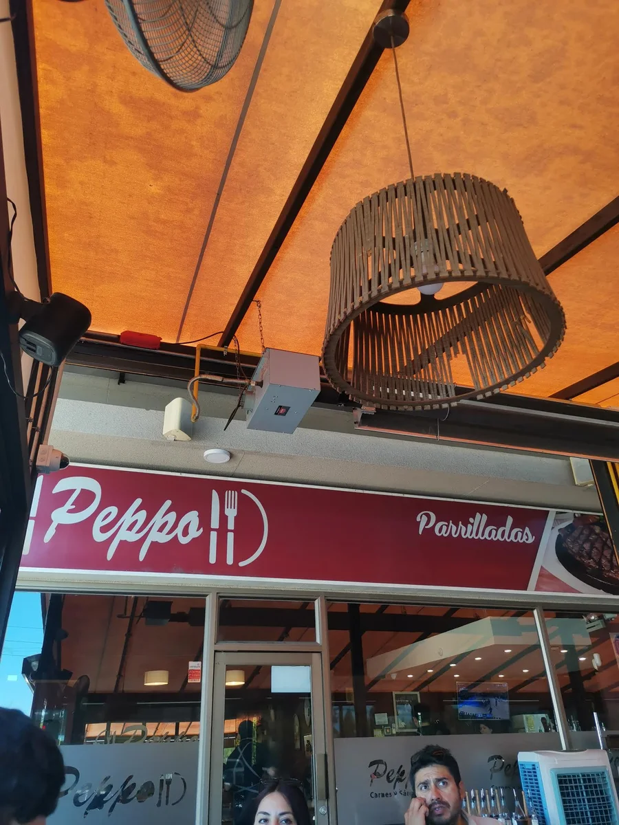 Fachada de Peppo Las Rastras: letrero burdeo con el logo sobre la entrada del local en 2 Norte