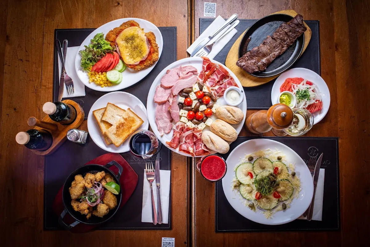 Mesa de Peppo con platos variados: carnes, ensaladas, pan y salsas al centro