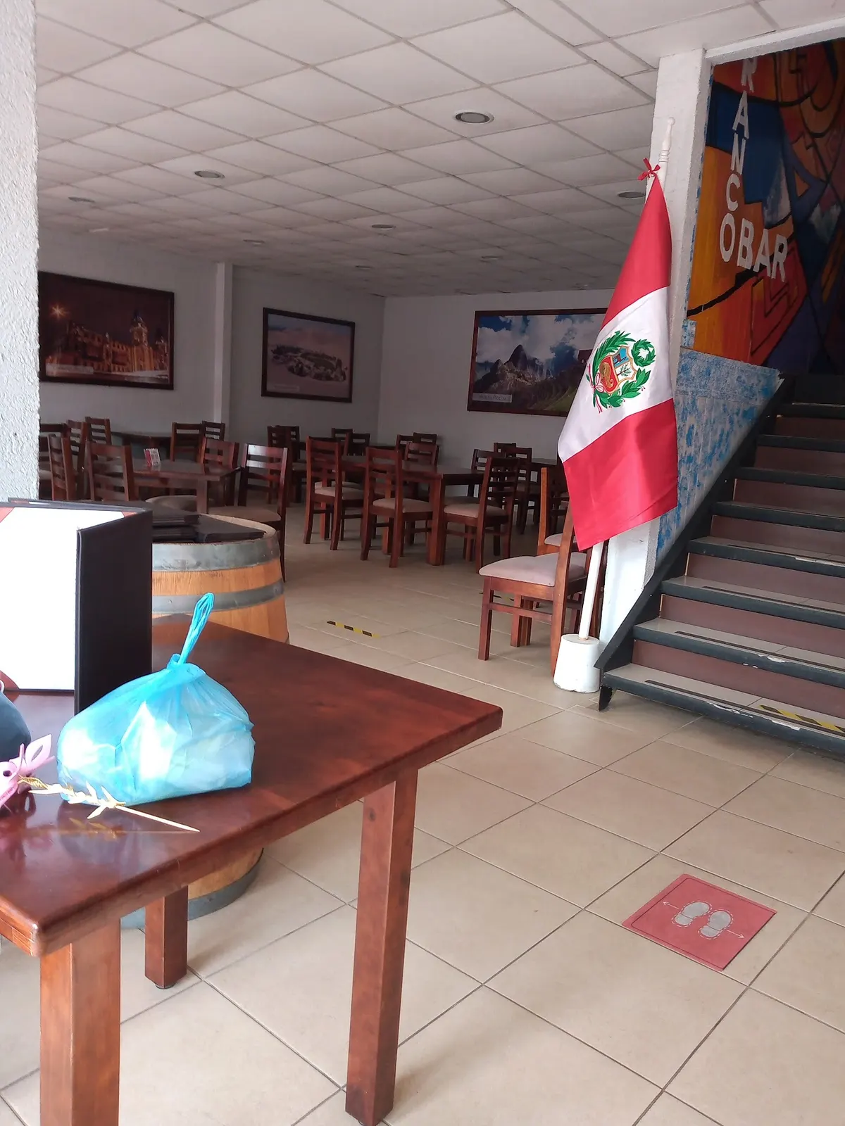 Salón del restaurante con la bandera del Perú y mantelería clara