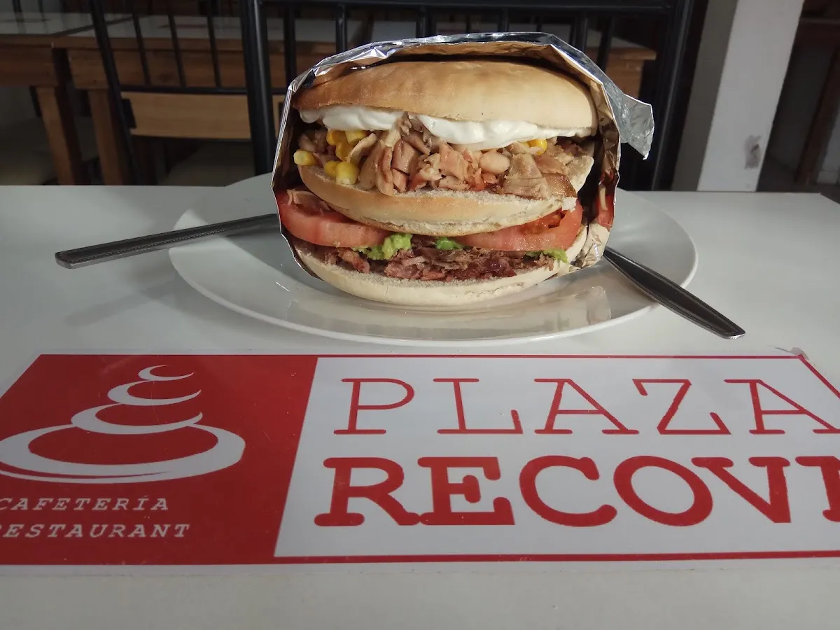 Sándwich de Plaza Recova servido en plato, con el logo de la cafetería en el mantel