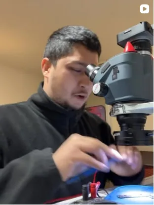 Técnico de Promax trabajando con microscopio en el banco de reparaciones