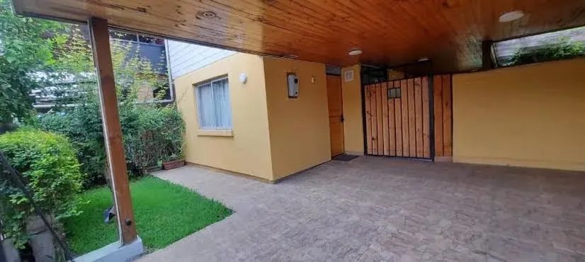 Terraza techada del hostal con mesa de madera y jardín al fondo